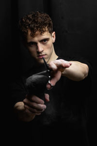 Close-up of young man with hands against black background