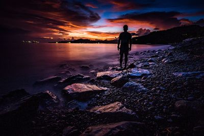 Silhouette man standing on beach against sky during sunset