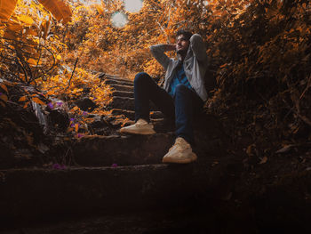 Man sitting on autumn leaves in forest