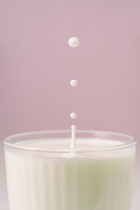 Milk drips into a transparent faceted glass.