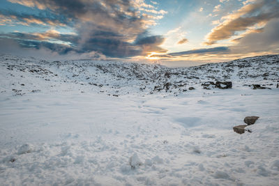 Scenic view of snow covered land against sky during sunset