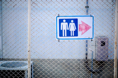 Close-up of toilet sign on fence