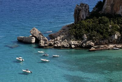 Boats docking in cala luna beach harbour with pristine turquoise water on sardinia island in italy