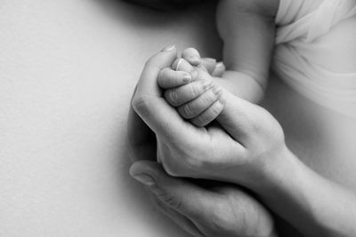 Cropped image of mother holding baby hand