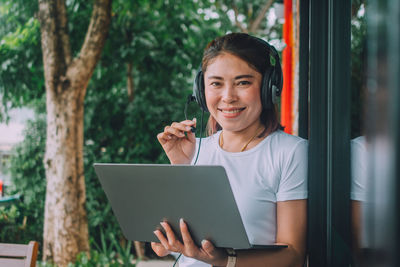 Portrait of smiling woman holding smart phone outdoors