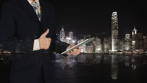 Man standing by illuminated buildings in city at night