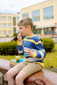 Full length of a boy holding food while sitting outdoors