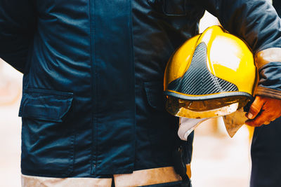 Midsection of firefighter holding helmet