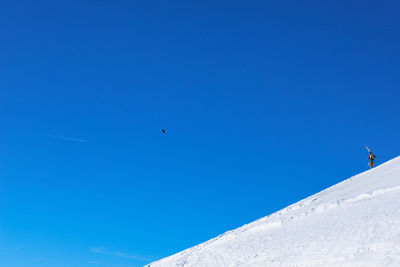 Low angle view of snowcapped mountain against blue sky