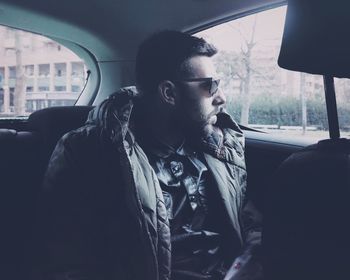 Young man looking through window while sitting in car