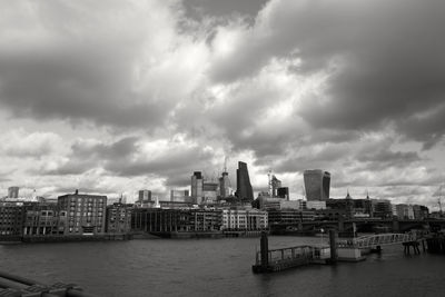 City at waterfront against cloudy sky