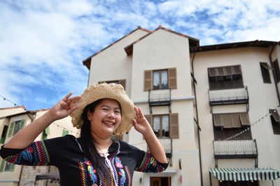 Portrait of smiling young woman against building