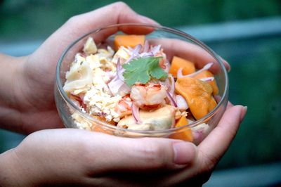 Close-up of hand holding ceviche in bowl