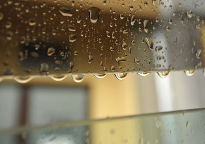 Raindrops on an opened window, yellow house on blurred background