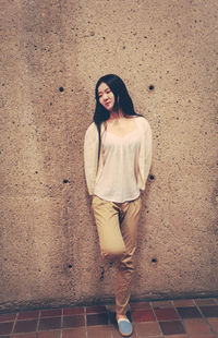Portrait of a smiling young woman standing against tiled wall