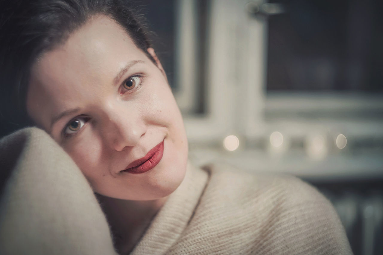 portrait, headshot, one person, real people, lifestyles, indoors, young adult, smiling, leisure activity, focus on foreground, looking at camera, front view, young women, happiness, looking, sitting, adult, beautiful woman, contemplation, human face