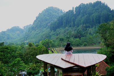 Rear view of men sitting on mountain against sky