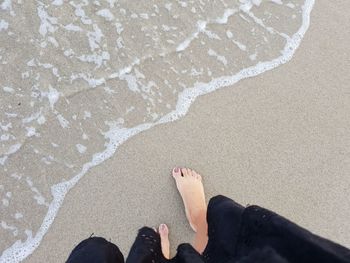 Low section of woman standing at beach