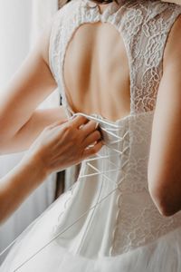 Cropped hand of bridesmaid adjusting bride dress