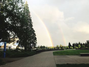 Rainbow over road against sky