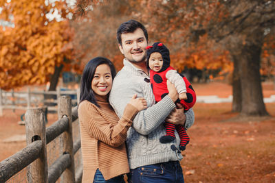 Portrait of parents with cute daughter in park during autumn