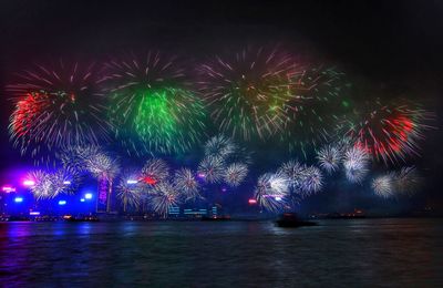 Low angle view of firework display over river at night