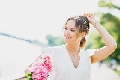 Portrait of woman with pink flowers against blurred background