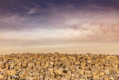 Cityscape against cloudy sky during sunset