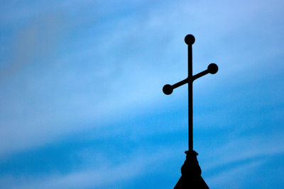 Low angle view of silhouette pole against blue sky