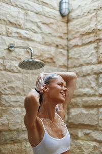 Portrait of young woman standing against wall