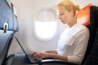 Businesswoman working on laptop sitting at airplane