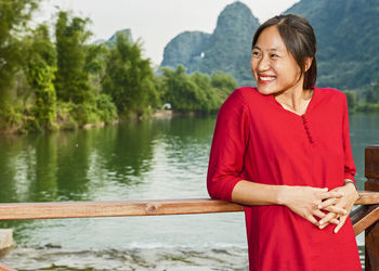 Beautiful woman resting her elbows on balustrade next to river li