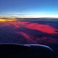 Airplane wing against sky during sunset