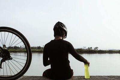 Rear view of cyclist against river