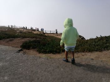 Rear view of people walking on street against sky