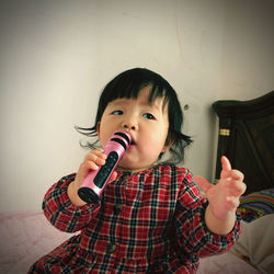 Portrait of cute girl holding camera at home