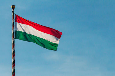 Hungarian national flag waving on blue sky background. hungary, hu 