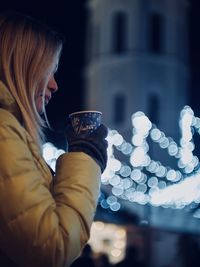 Close-up of woman drinking coffee in city during night