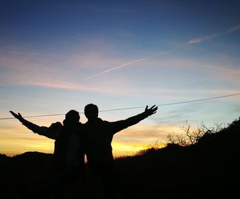 Silhouette men standing against sky during sunset