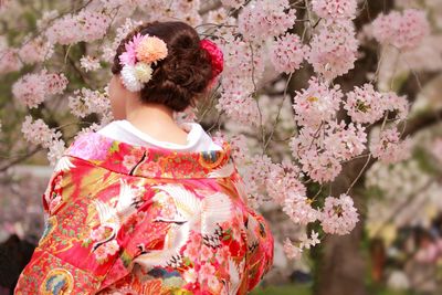 Rear view of woman against pink flowering tree