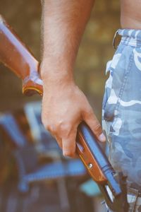 Midsection of man holding rifle