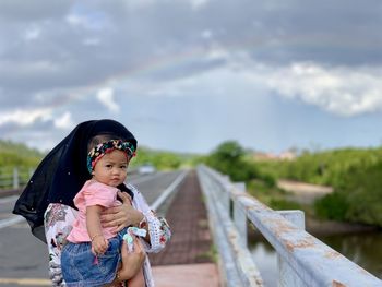 Portrait of cute girl against cloudy sky