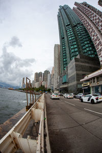 Modern buildings by street against sky in city