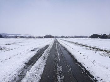 Snow covered road against clear sky during winter