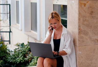 Young woman using laptop while sitting on table