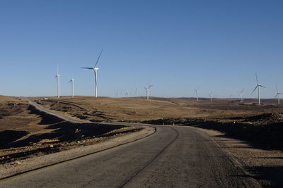 Road passing through landscape against clear blue sky