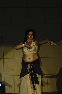 Portrait of young woman standing against wall