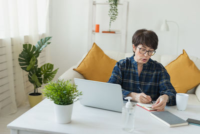 Portrait of young woman using digital tablet while sitting at home