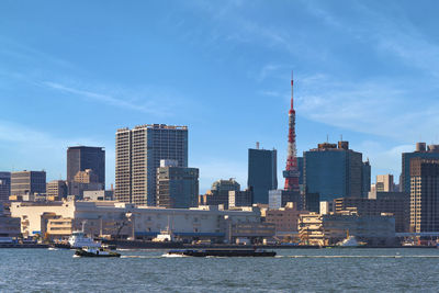 Barges towed by tugboats sailing in front of the shibaura terminal on tokyo port with  tokyo tower.