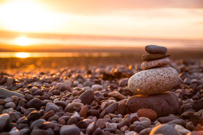 Stack of pebbles at beach during sunset